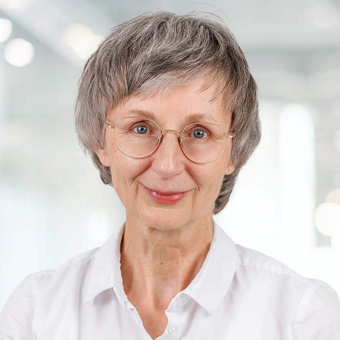Portrait of a smiling older woman with grey hair and glasses.