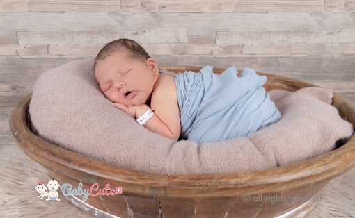 Neugeborenes schläft friedlich in einem Korb, eingewickelt in eine blaue Decke.