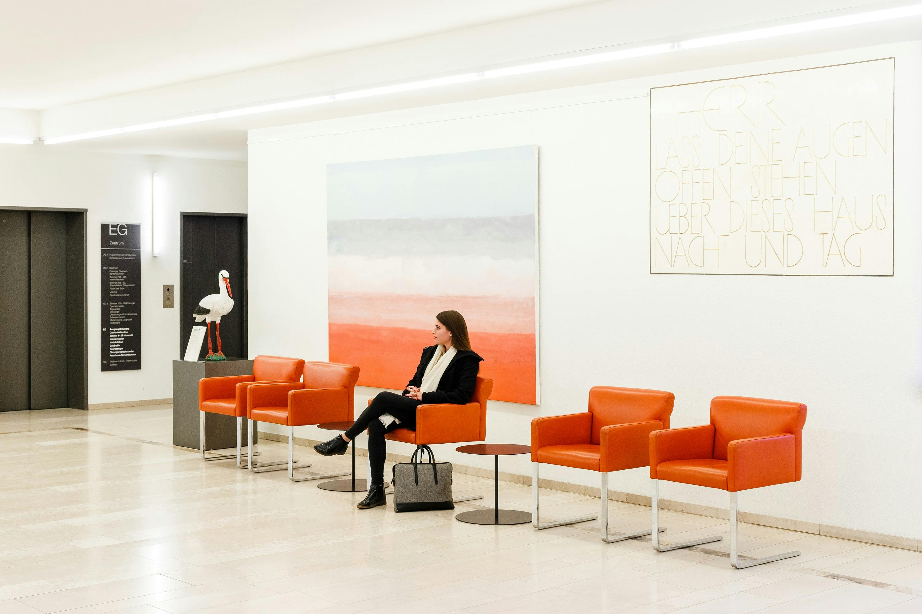 Frau sitzt in moderner Galerie mit Gemälden und Skulptur.