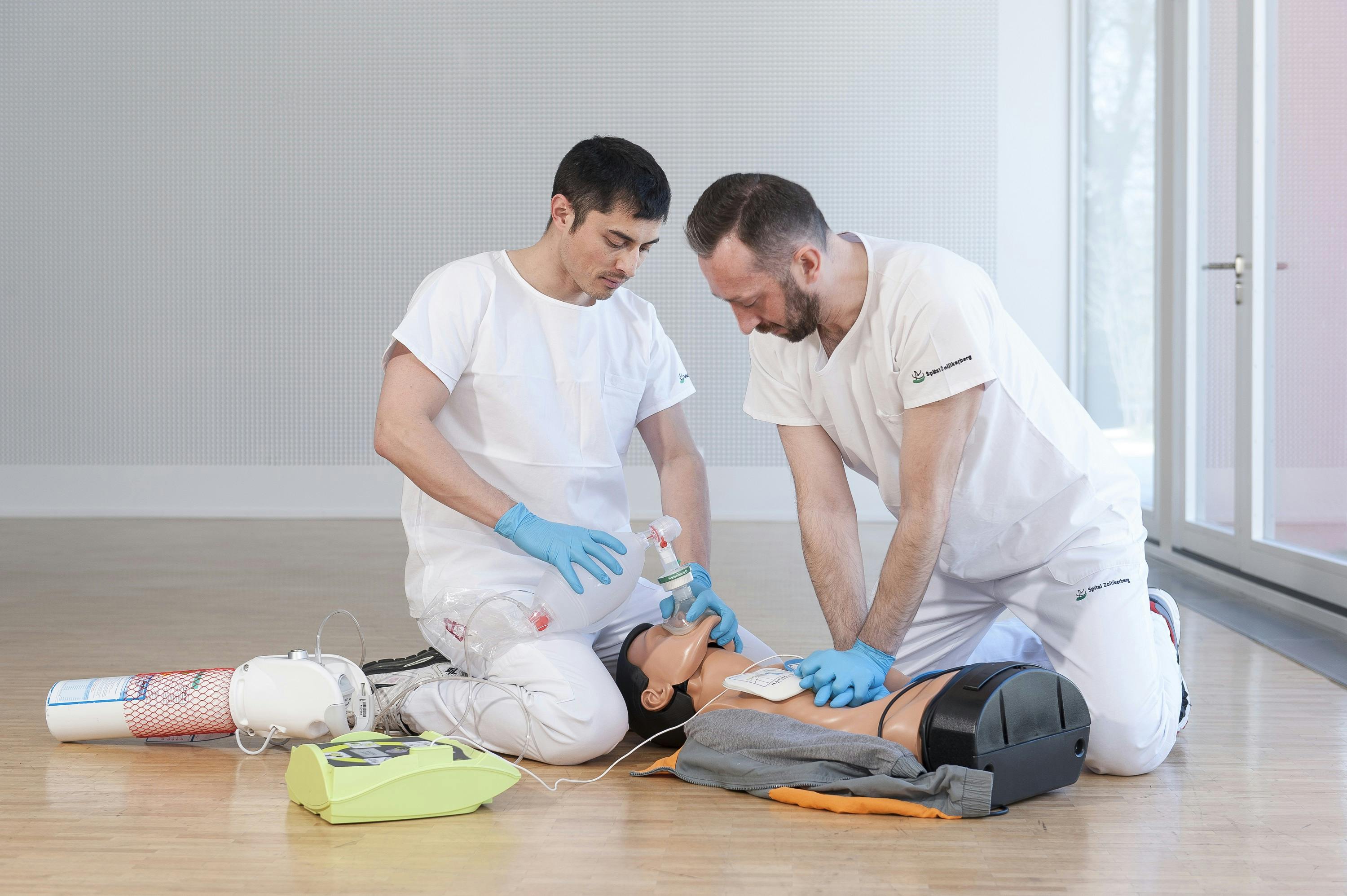 Two paramedics carry out resuscitation measures on a manikin.