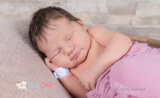 Sleeping newborn baby wrapped in a pink blanket.