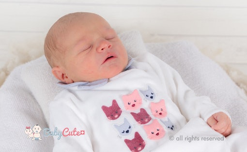 Sleeping newborn baby in clothes with cat design.