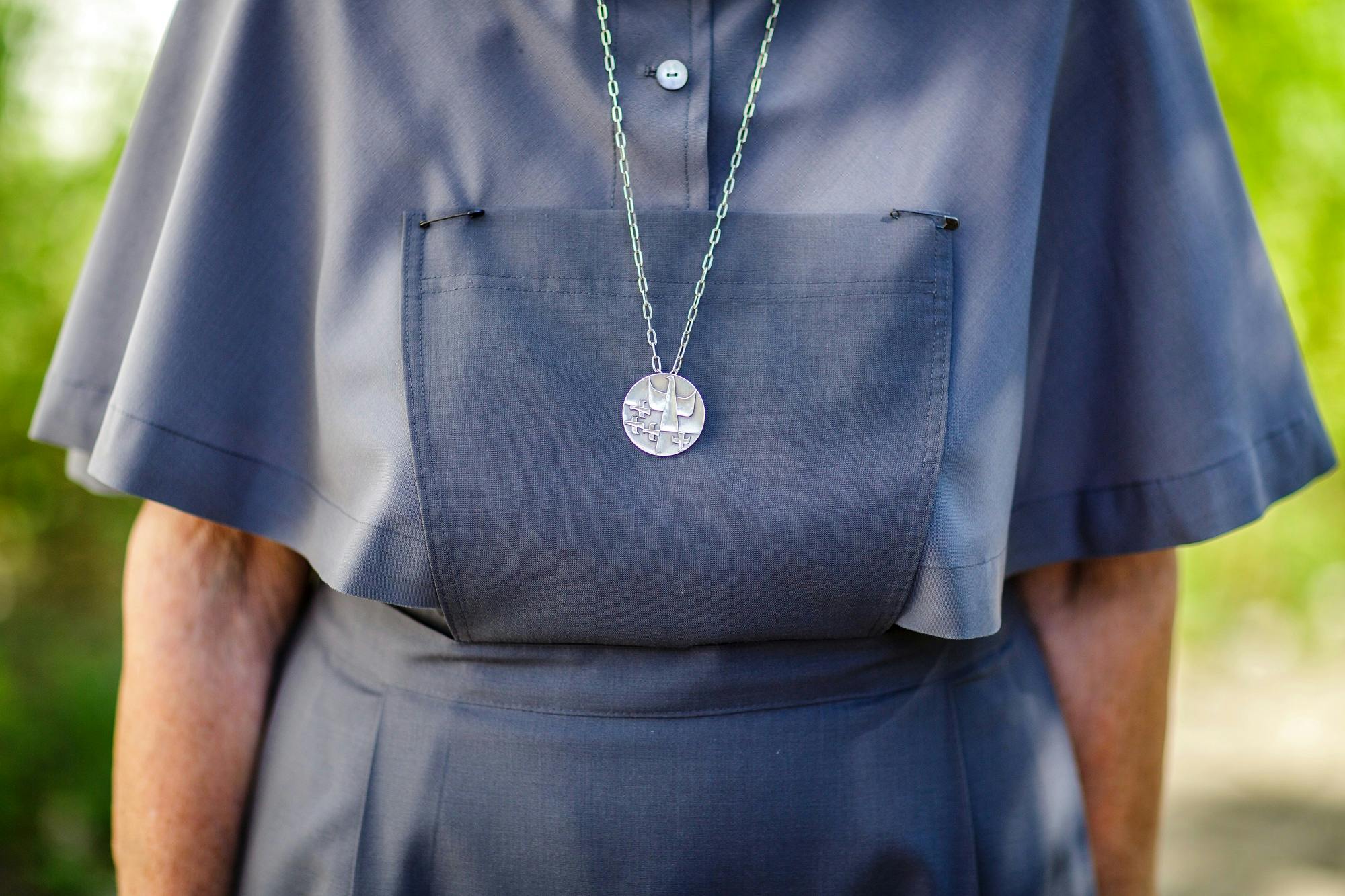 Person wears shirt with chain and round pendant.