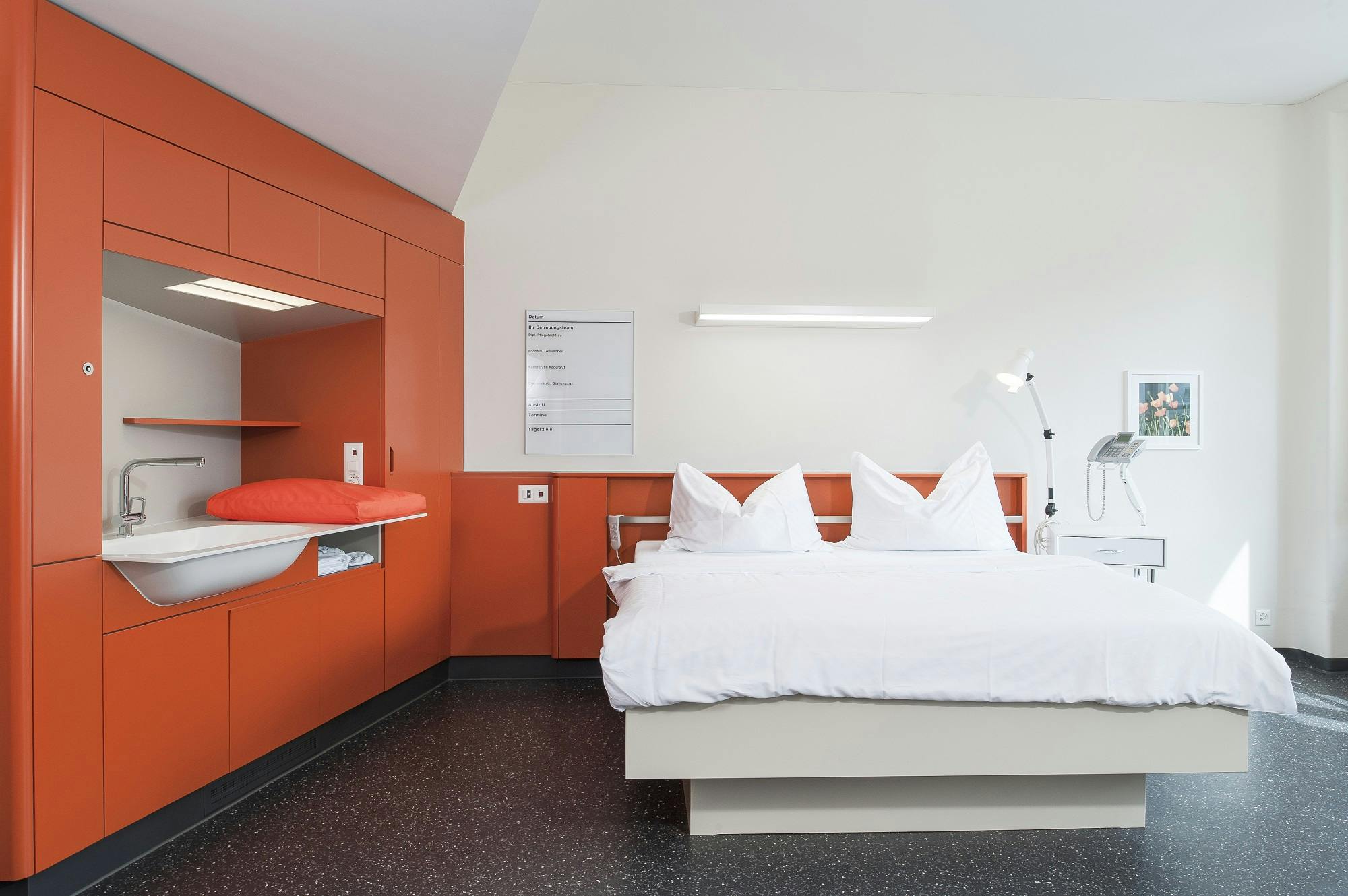 Modernes Hotelzimmer mit orangefarbener Dekoration und Doppelbett.