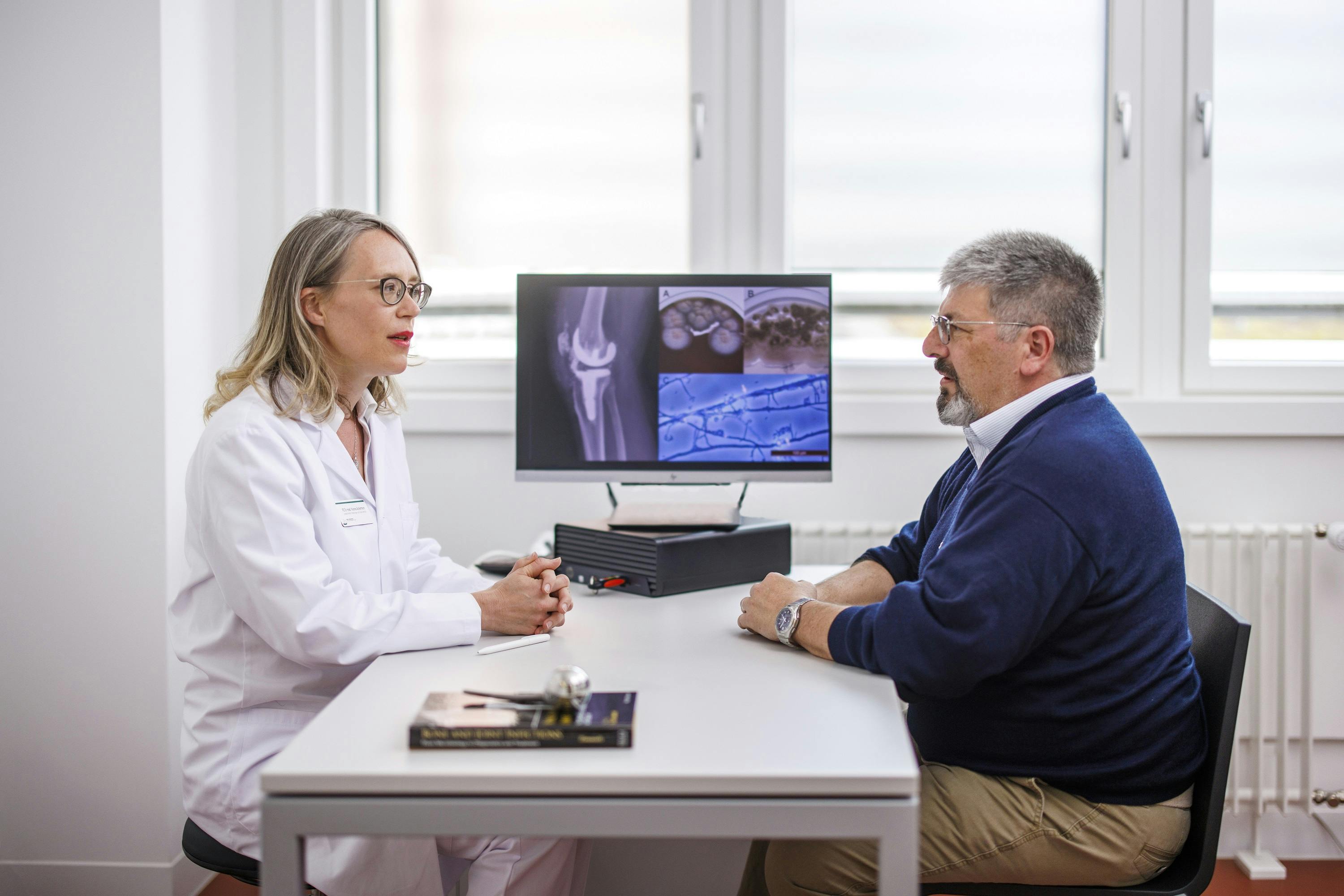 Ärztin bespricht Röntgenbilder mit Patienten im Büro.