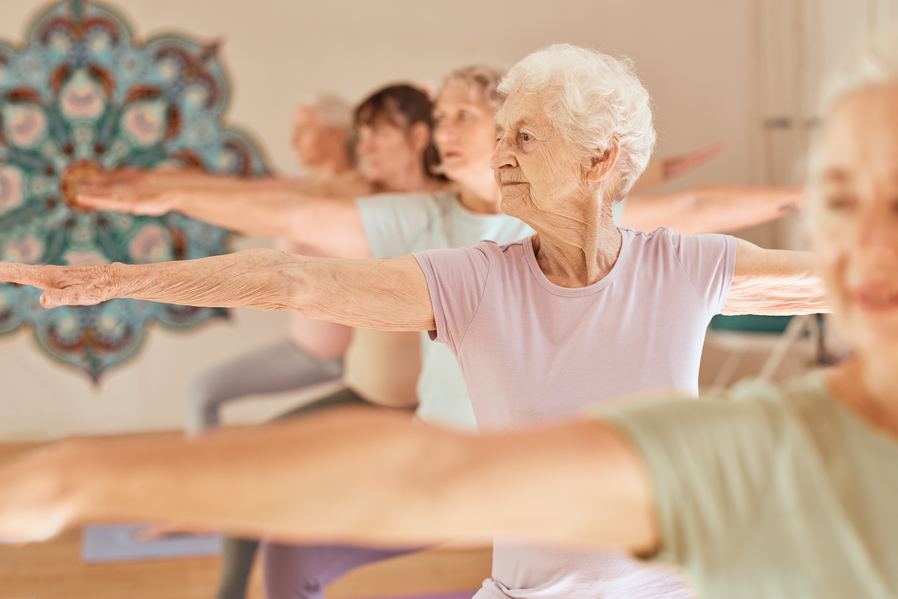 Senioren bei Yoga-Übungen in einem hellen Raum.