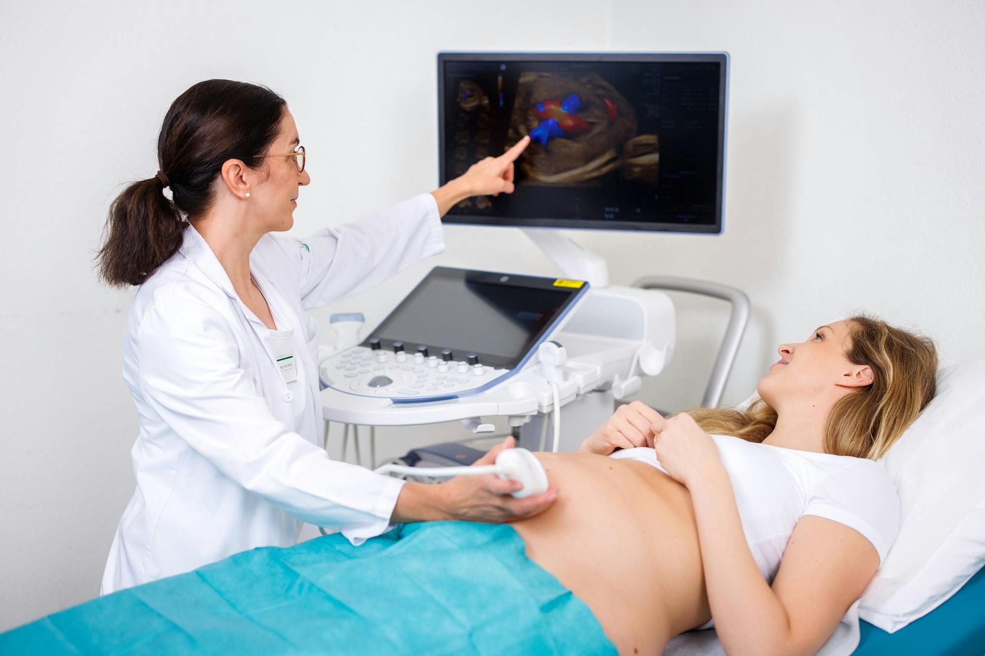 Doctor performs ultrasound examination on patient and points to ultrasound image on monitor.