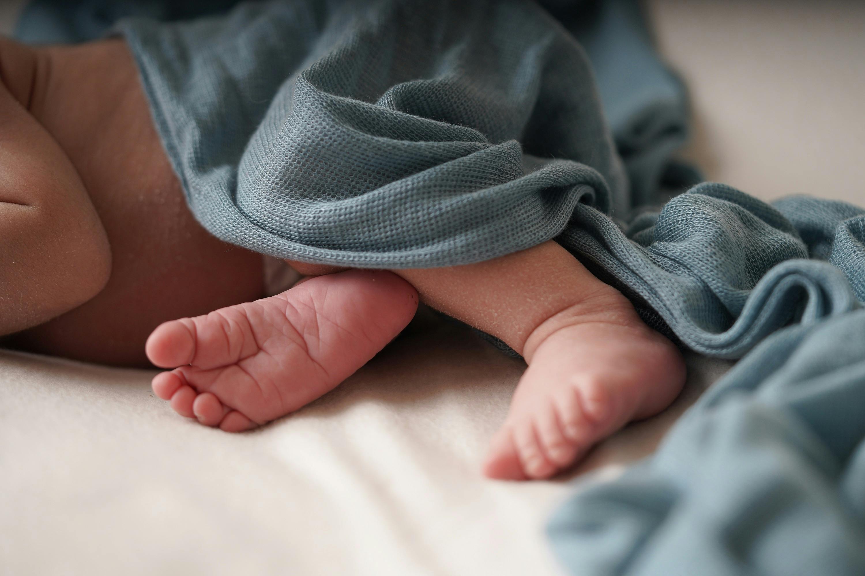 Babyfüße unter einer blauen Decke.
