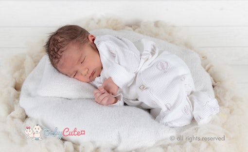 Schlafendes Neugeborenes auf einer weißen Decke.
