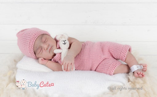 Schlafendes Baby in rosa Kleidung mit Kuscheltier.