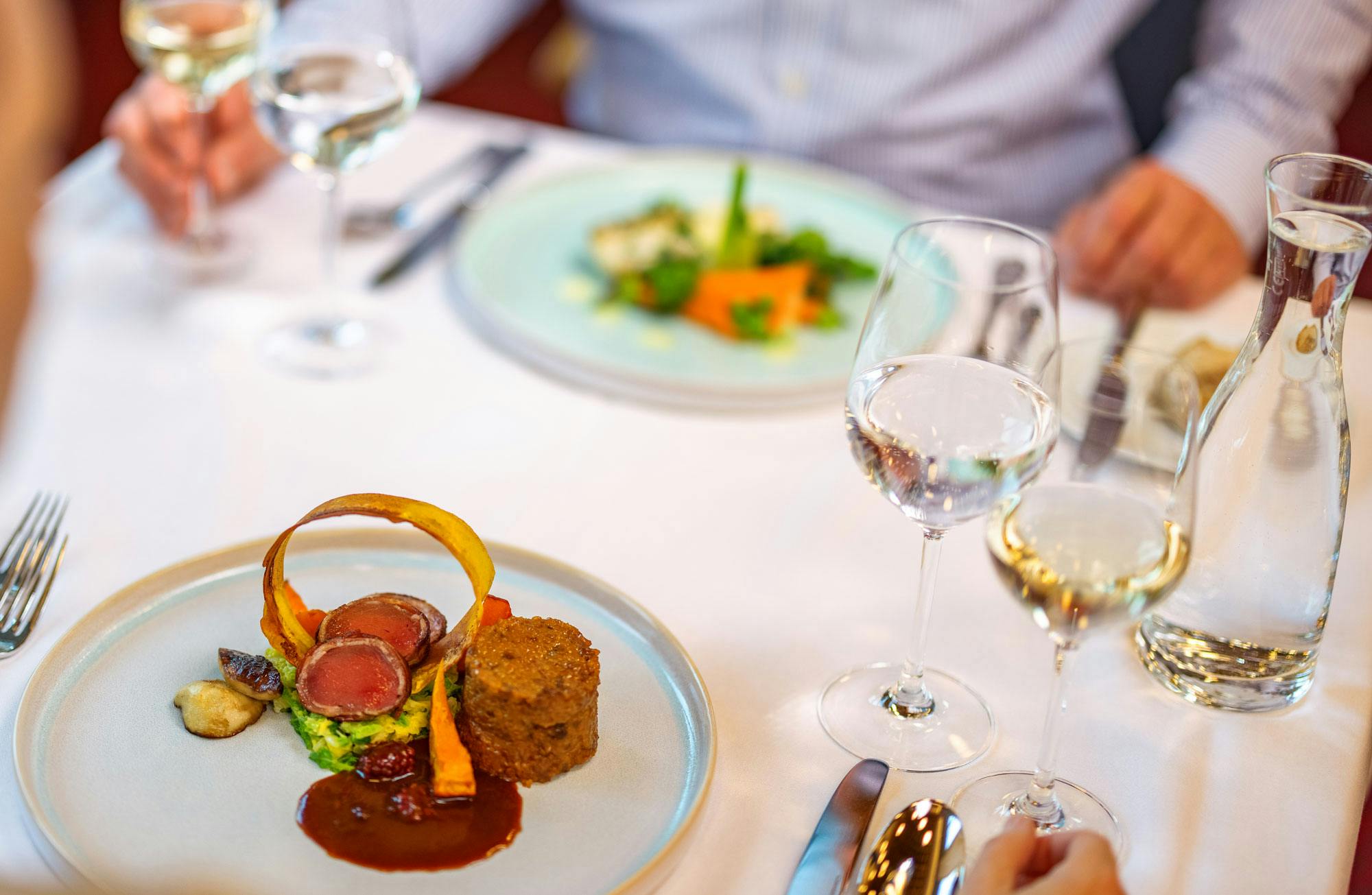 Gourmet meal in a restaurant with wine glasses and blurred background.