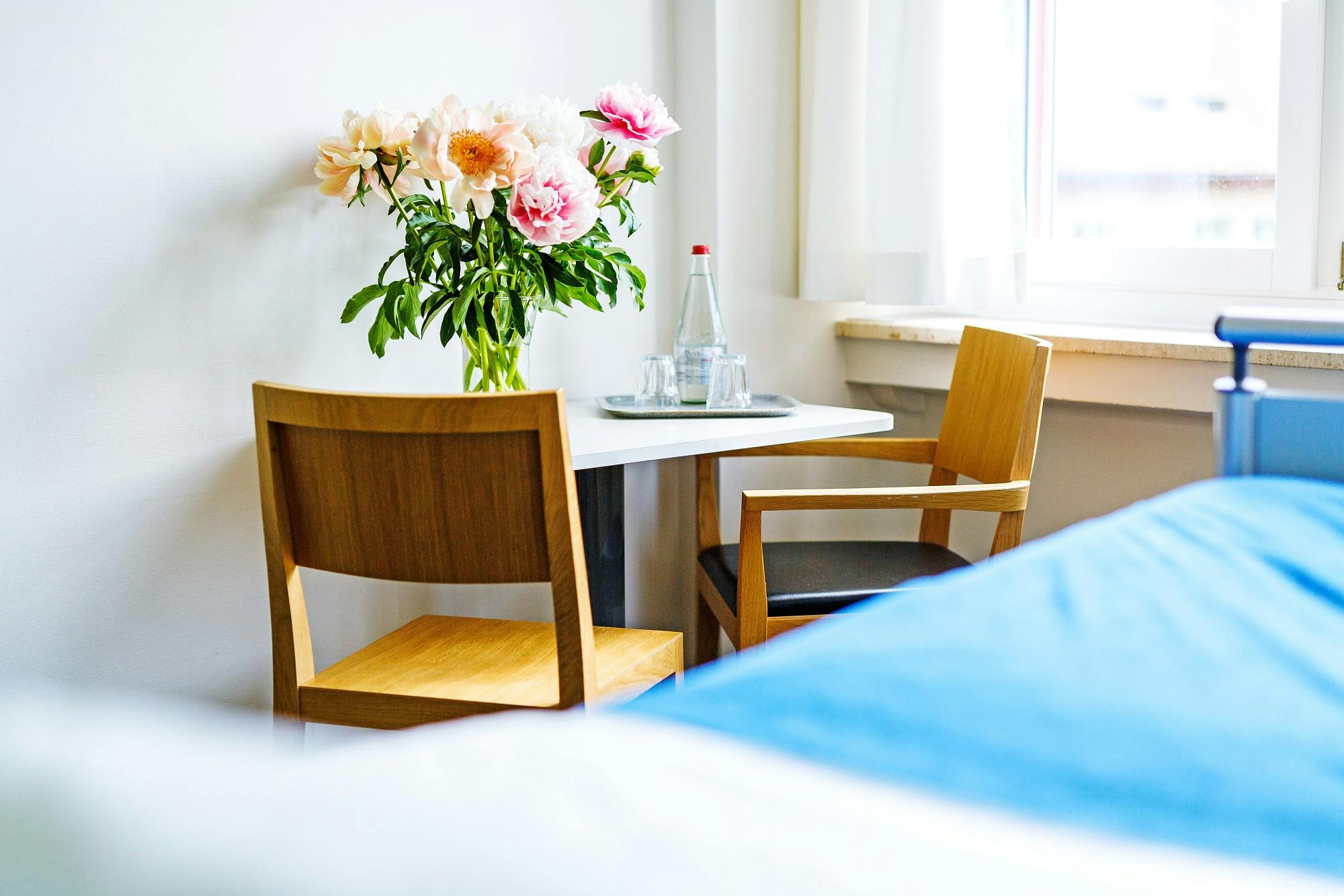 Gemütliches Zimmer mit Blumenstrauß auf dem Tisch und Holzstühlen.
