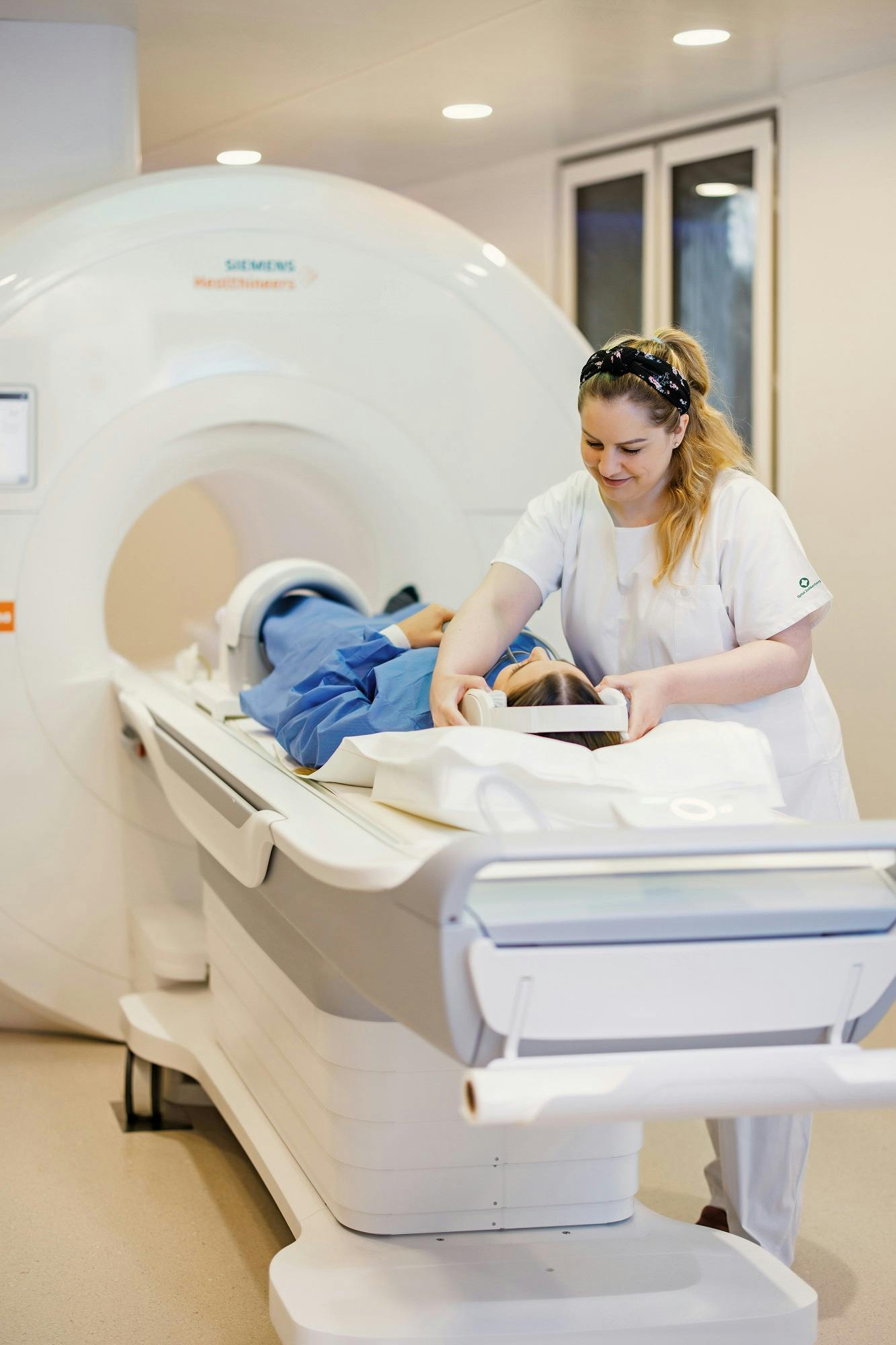 Medizinische Fachkraft bereitet Patienten auf MRT-Untersuchung vor.