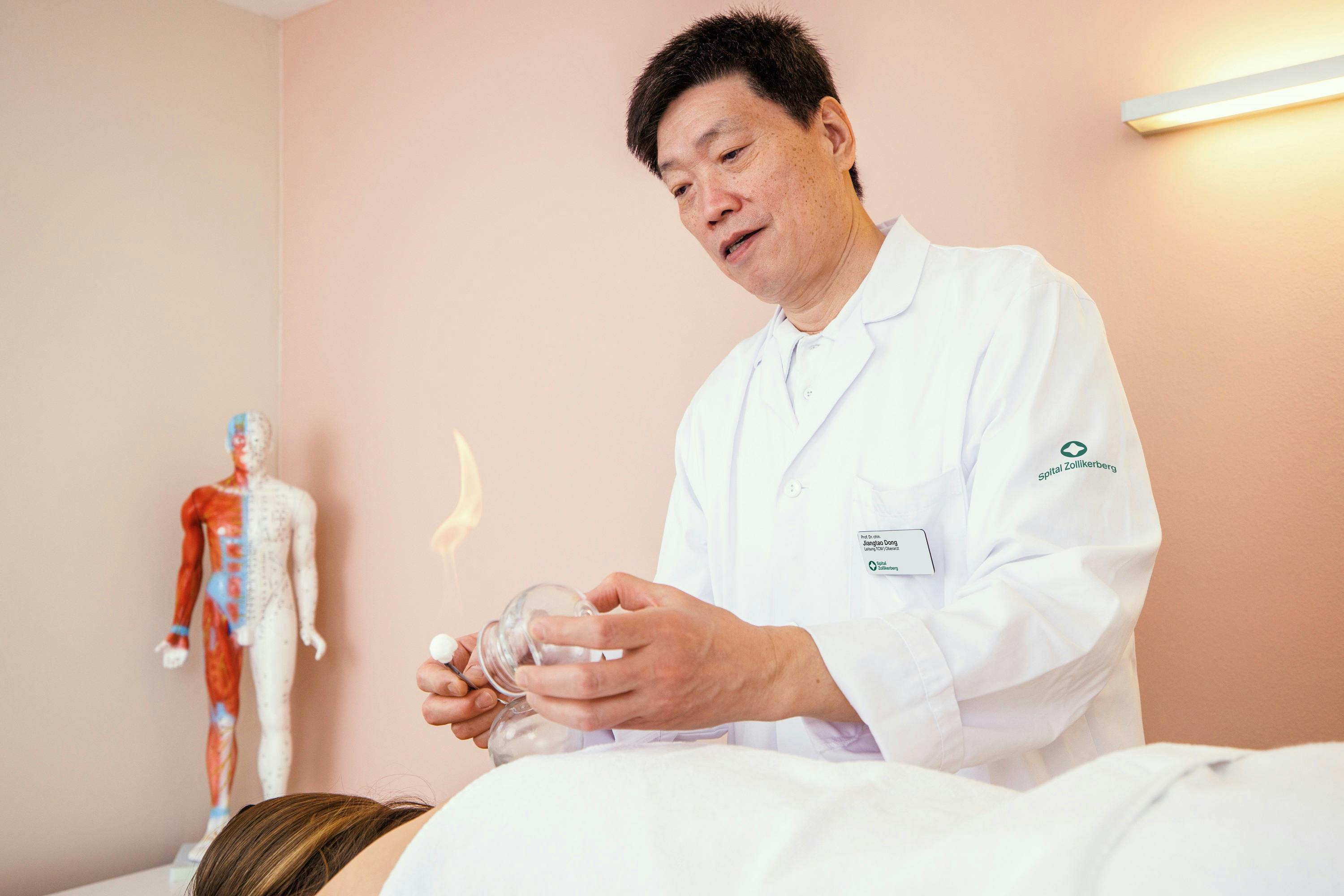 Alternativbeschreibung: Asiatischer Arzt führt Schröpftherapie bei einem Patienten durch.