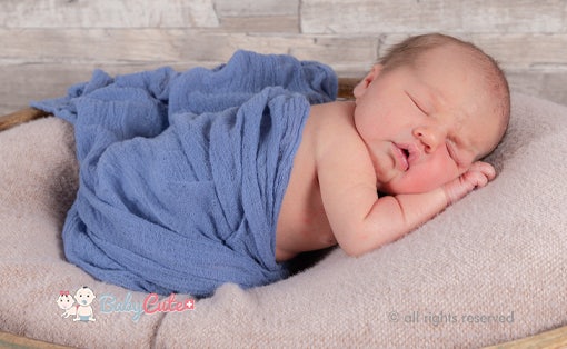Schlafendes Neugeborenes in blauer Decke gewickelt.