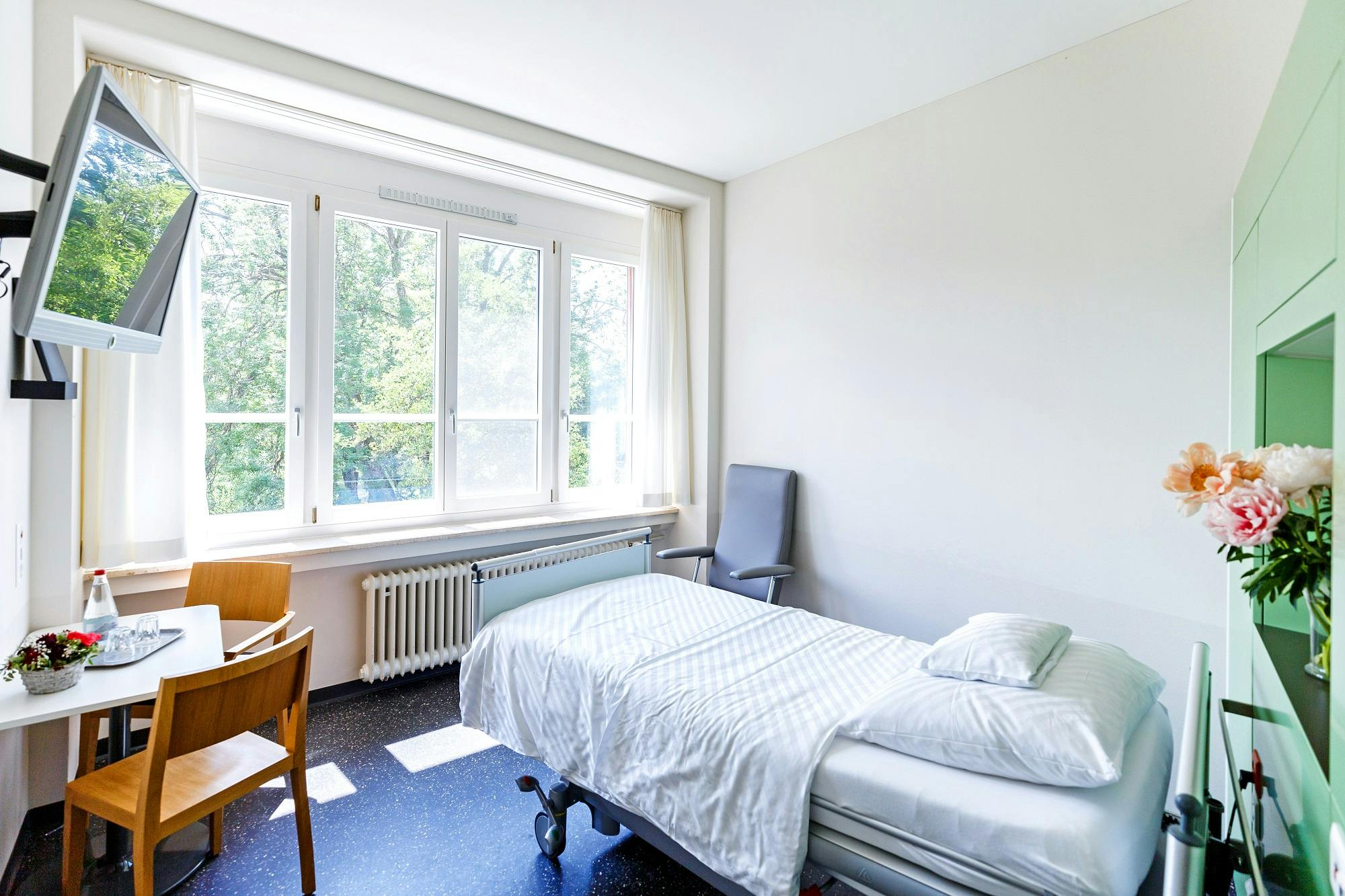 Helles, einfaches Schlafzimmer mit Einzelbett und Schreibtisch an Fensterfront.