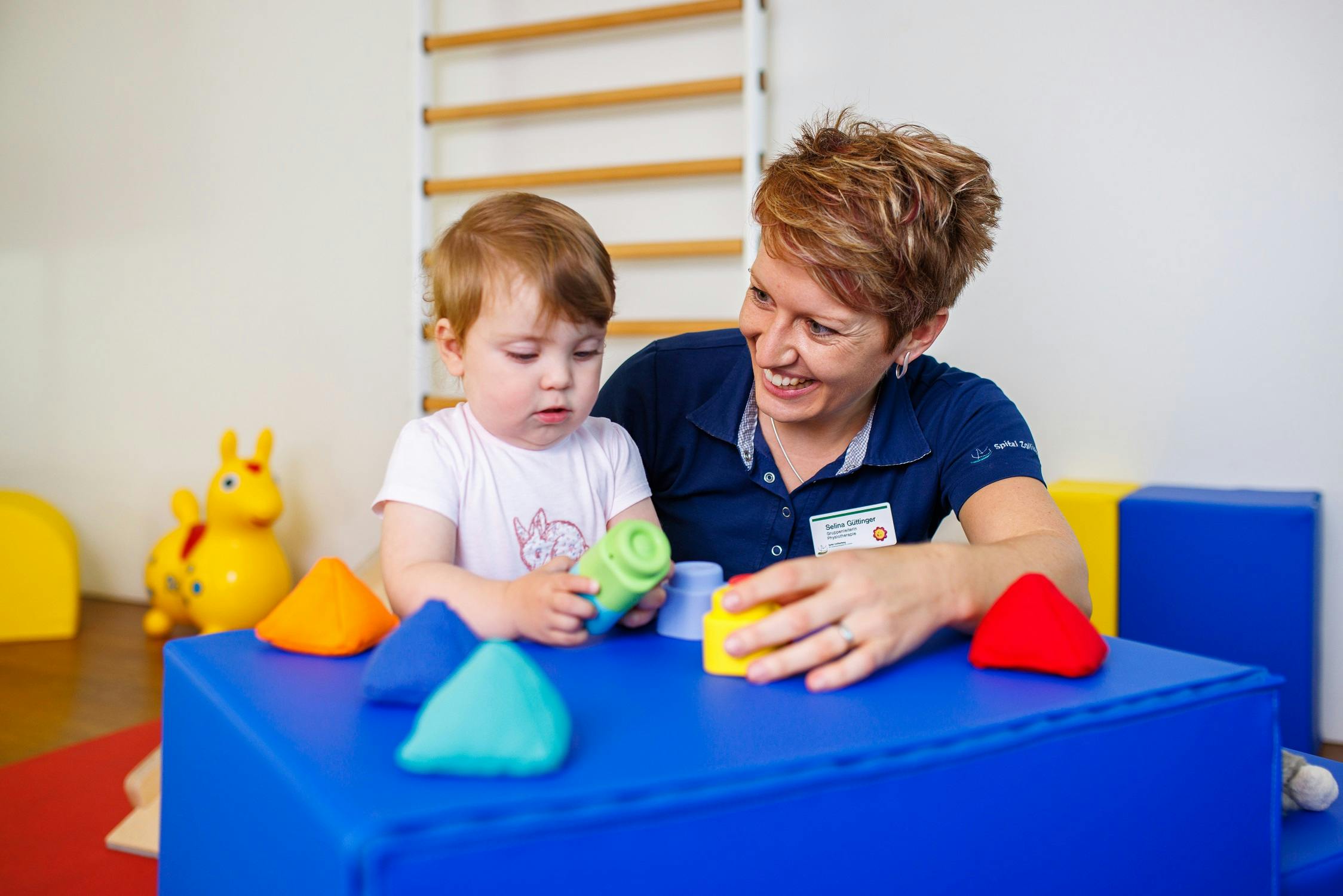 Therapeutin arbeitet mit Kleinkind an Feinmotorik mit Spielzeug in einer Kindertherapieeinrichtung.